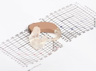 A hearing aid lies on a math problem