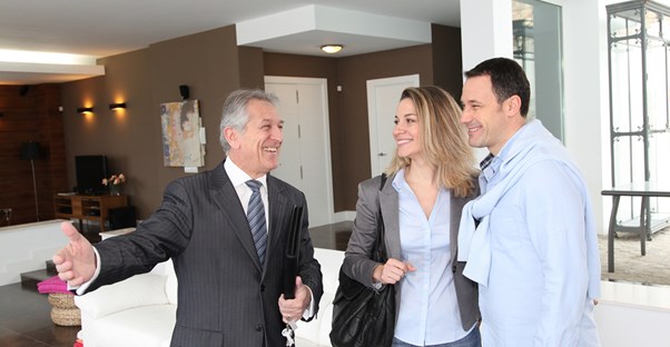 A real estate agent shows a young couple a lovely home