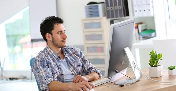 A man wearing flannel works on his computer