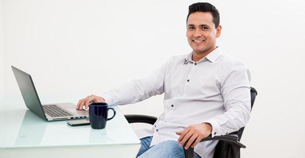 Man takes a break from working on his laptop to smile for the camera