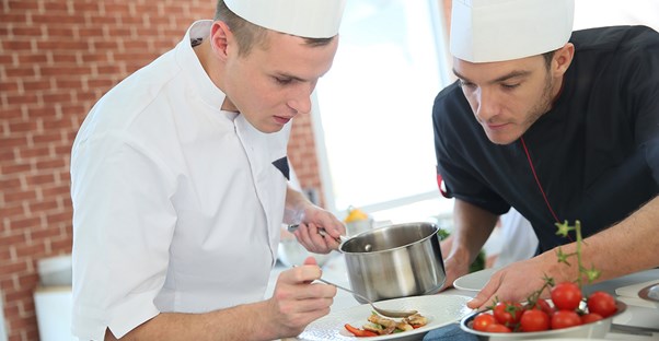 A chef teaches a cook what to do in the kitchen