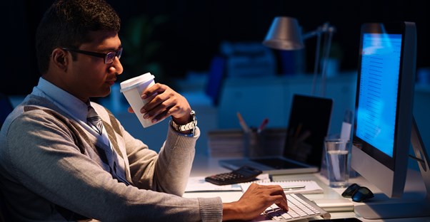 A computer programmer drinks coffee during a late night of work