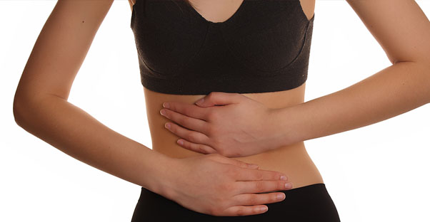 a woman holds her stomach as it aches from IBS