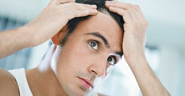 a man examines his hair line for hair loss
