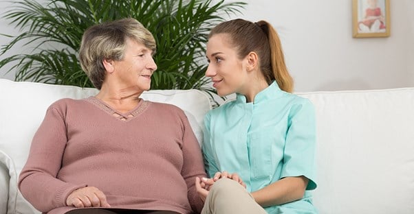 Older woman and younger woman sitting on a couch talking