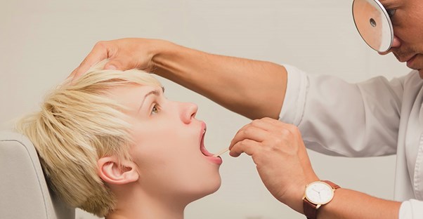 A doctor examines a patient's mouth