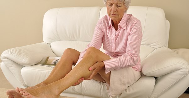 Woman on couch experiencing leg pain