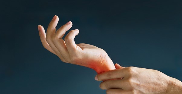 woman holding wrist because she is experiencing chronic pain
