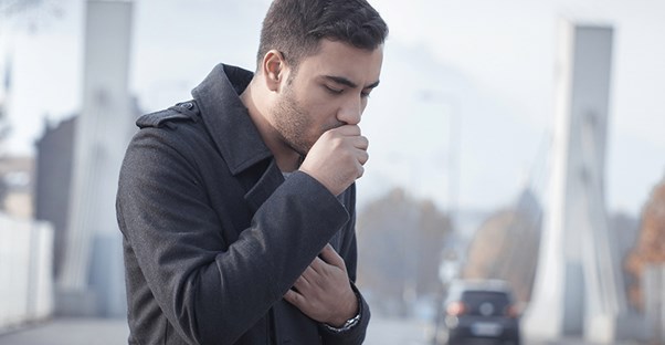 man walking down the street coughing