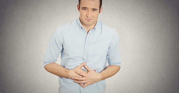 Man holding stomach in pain. Pancreatitis causes.