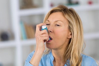 Woman with asthma using an inhaler
