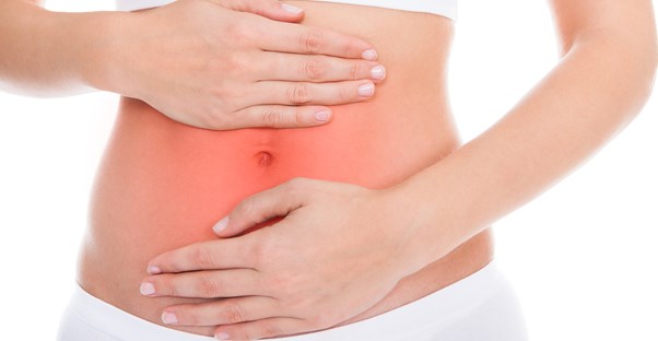 a woman holds her bare stomach with pains from crohns disease