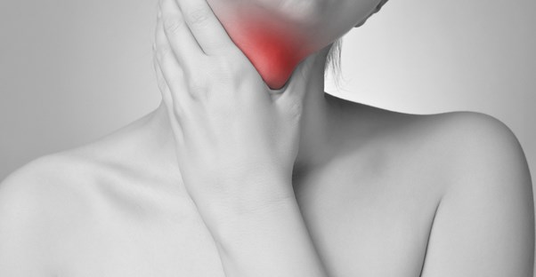 black and white image of a woman's upper torso where she hold's her throat that is colored red indicating swelling