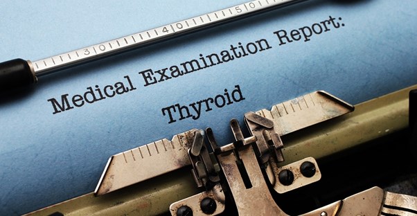 a typewriter typing a medical examination report that is titled thyroid