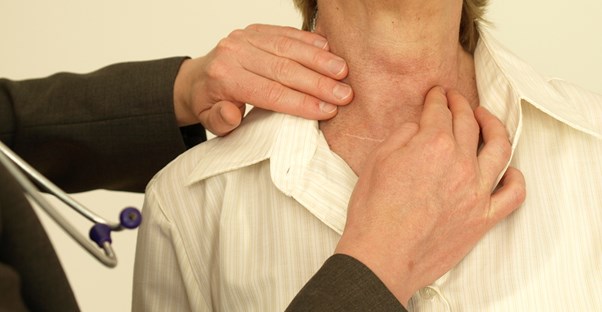 a doctor examines a patient for signs of hyperthyroidism