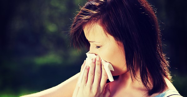 a woman with hay fever symptoms blows her nose