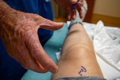 A doctor examines a patient's leg while they sit in a hospital bed