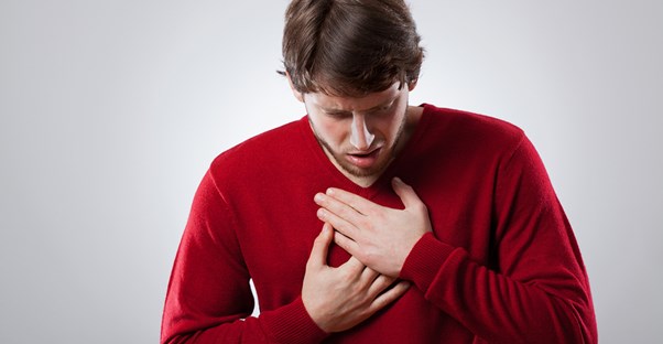 a man grabs an area where his is experiencing chest pain