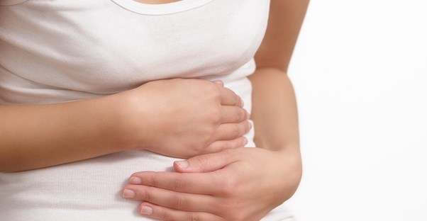 a woman holds her stomach from the symptoms of ulcerative colitis