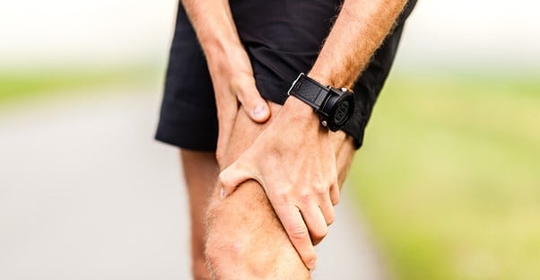 a runner grasps an area of knee pain