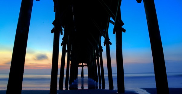 a view underneath a pier leading out into the ocean