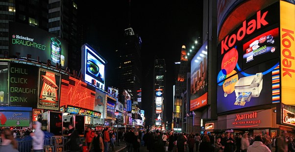 tourists crowd Times Square and take pictures of all the lights and billboards