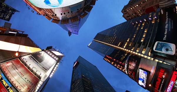 a view upwards towards the sky through the buildings from the center of Times Square