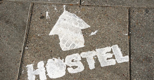 the word hostel is spraypainted on the ground with an arrow pointing the way