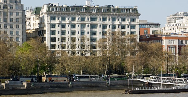 the Savoy London Hotel sits among other buildings on the banks of the Thames