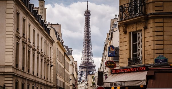 the eiffel tower peeks through buildings in Paris