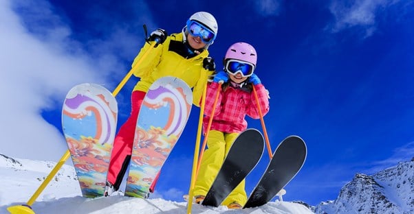 a mom and daughter get set to ski down a mountain slope