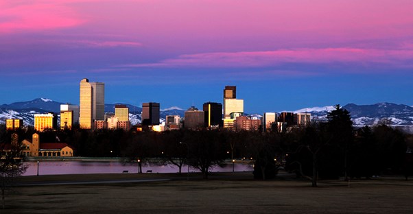 the skyline of Denver in front of a pink sunset sky
