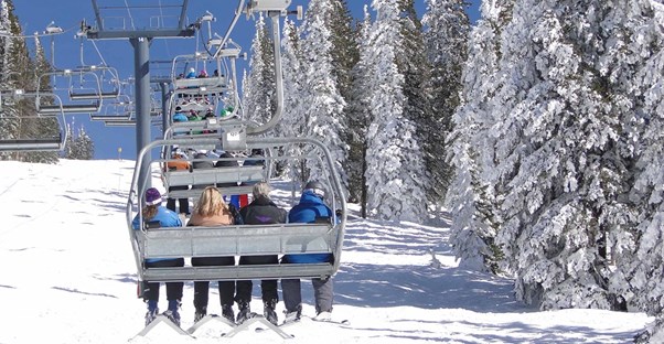 skiers ride up a chair lift to the top of a ski run