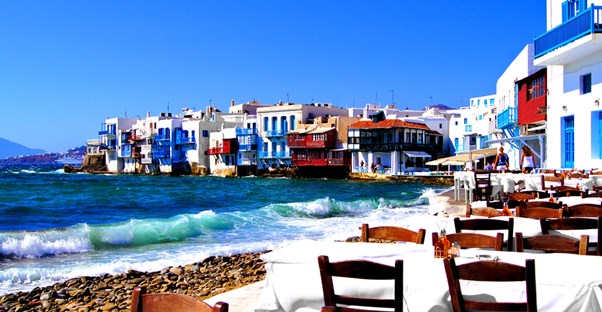 a greek restaurant patio sits allong the shore of the mediterranean sea