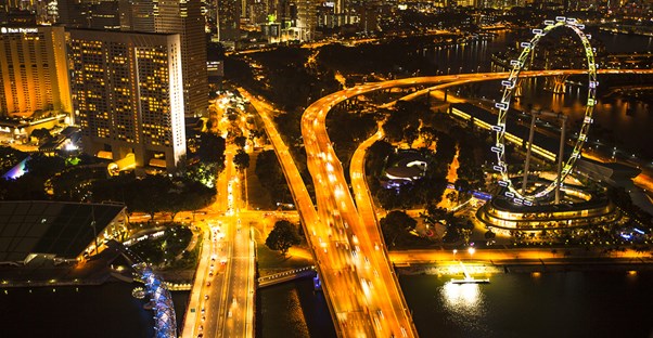 a singapore road is lit up at night by the headlights of cars and the singapore flyer ferris wheel