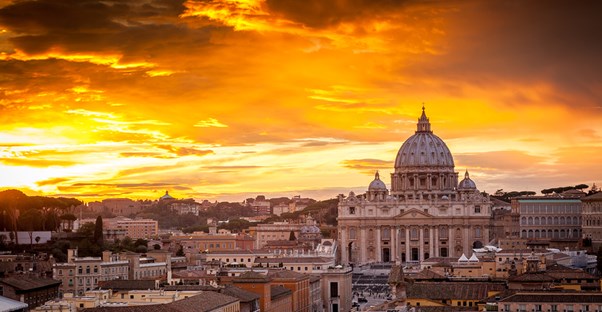 the sun rises behind st. peter's basilica