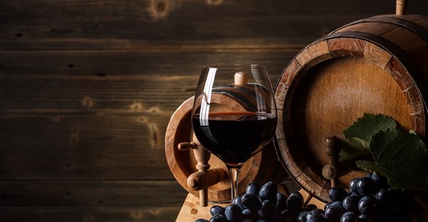 a glass of wine sits in front of a wine barrel and sonoma california grapes