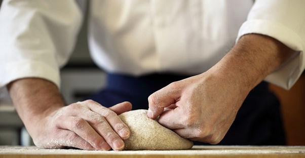 A baker kneeds dough