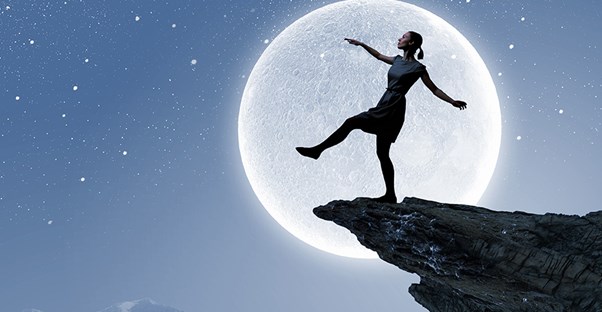 Woman with the moon behind her about to step off a cliff