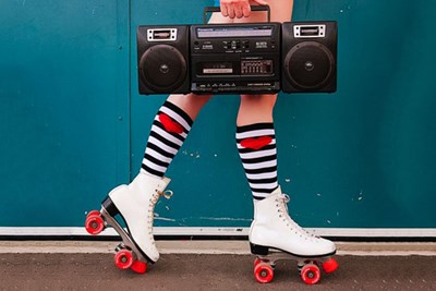 Woman wearing white roller skates with red wheels carrying a boombox