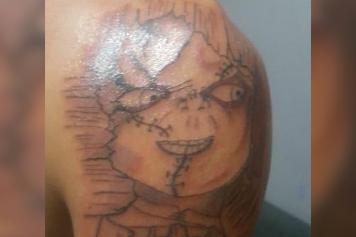 Black and grey Chucky tattoo on the left inner arm