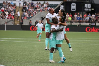 nwsl players celebrate after scoring a goal during a soccer game