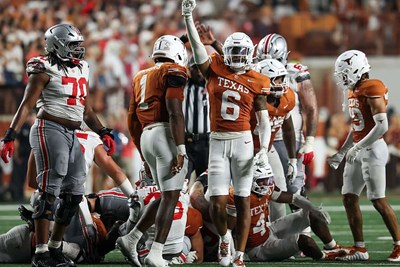 a member of the texas football team raises his hand in celebration during a game