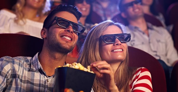 A couple shares popcorn while watching a 3D movie