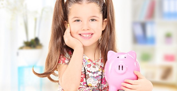 a young holds a pink piggy bank filled with her allowance money