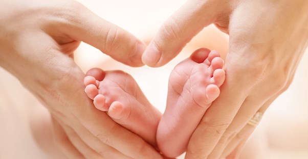 adult hands hold a small adopted baby's feet