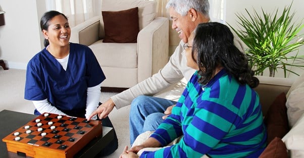 An elderly man and his daughter speak to a representative from a potential senior living community.