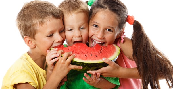 Three kids excitedly eat watermelon after learning about healthy snacks.