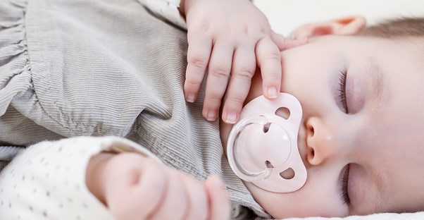 A baby sucking on an orthodontic pacifier