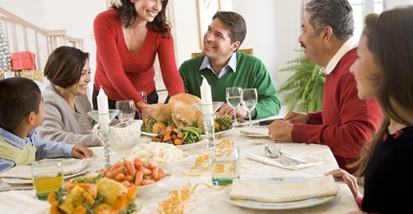 A woman smiling at her in-laws over a holiday dinner.